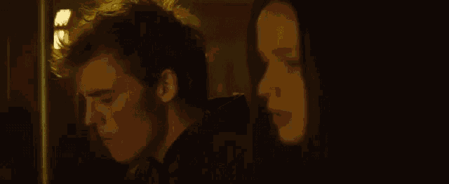 a man and a woman are standing next to each other in a dark room looking at each other .
