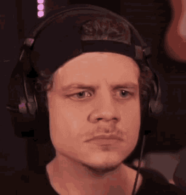 a man wearing headphones and a hat is making a face .