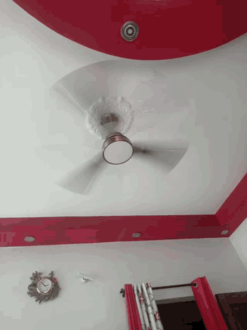 a ceiling fan is turned on in a room with a clock on the wall