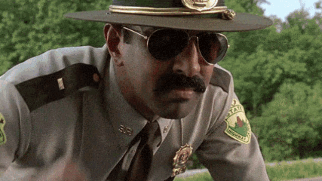 a man in a sheriff 's uniform and hat is wearing sunglasses and a patch that says highway .