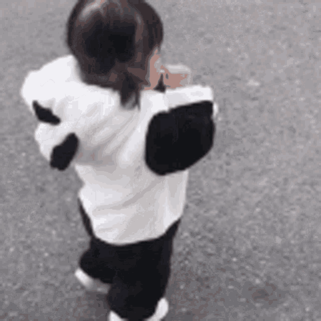 a little girl is wearing a panda costume and walking down the street .