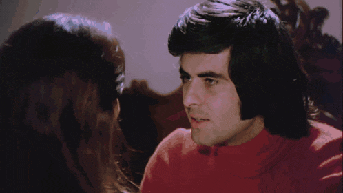 a man in a red shirt is hugging a woman in a white shirt