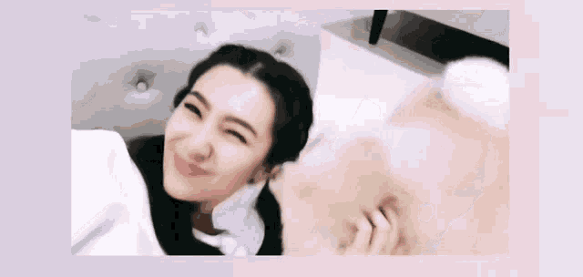 a woman is laying on a bed playing with a dog .