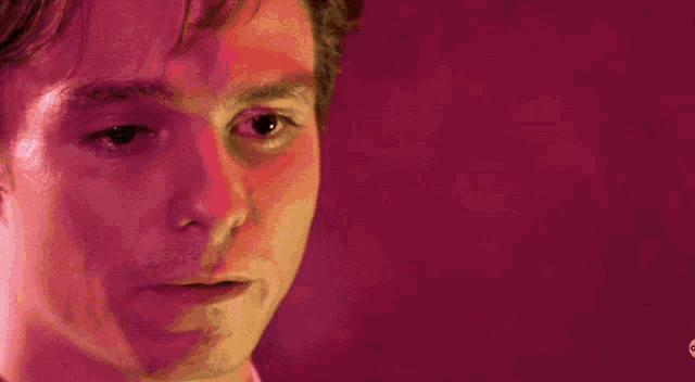 a close up of a man 's face against a pink background