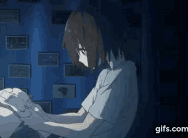 a girl is sitting at a desk in front of a wall with pictures on it