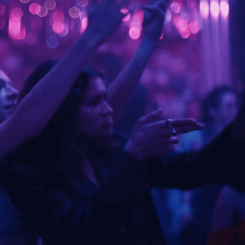 a woman is dancing in a dark room with purple lights