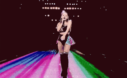 a woman is dancing on a stage with a microphone in her hand .
