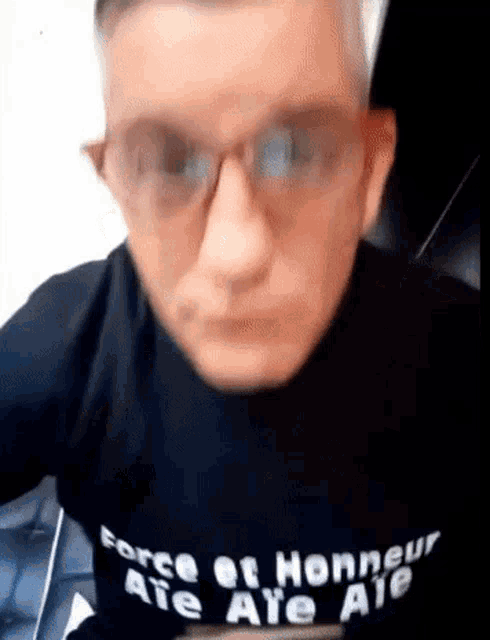a man wearing glasses is wearing a black shirt that says force et honneur ate ale ale