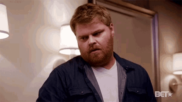 a man with a beard is standing in front of a mirror in a bedroom .