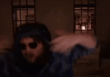 a man is wearing headphones and sunglasses and dancing in a dark room .