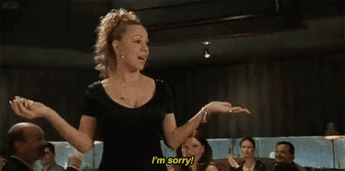a woman in a black dress is standing in front of a group of people and saying `` i 'm sorry '' .