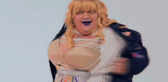 a woman wearing a purple jacket and shorts is dancing in front of a white backdrop