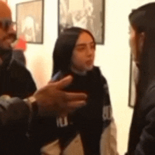 a man and a woman are talking to each other in a room with pictures on the wall .