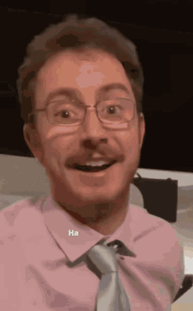 a man wearing glasses and a pink shirt has the word ha written on his neck