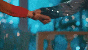 a close up of two people holding hands in a room .