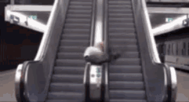 a person is sitting on top of an escalator in a building .
