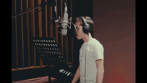 a young boy is singing into a microphone in a recording studio
