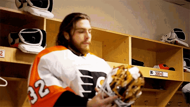 a hockey player with the number 32 on his jersey is standing in a locker room