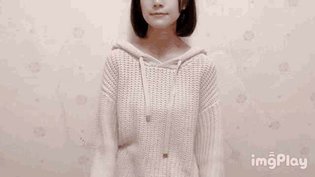 a woman is wearing a white sweater with a hood and the words imgplay below her