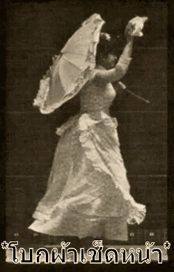 a woman in a long white dress is holding an umbrella .
