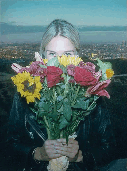 a woman holding a bouquet of flowers with a city in the background
