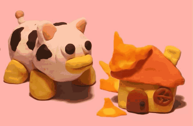 a pig and a house made of clay on a pink surface