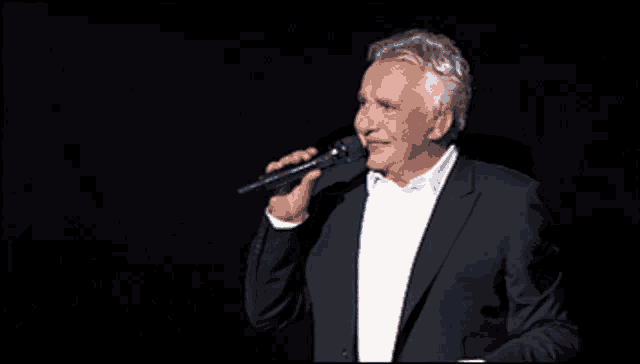 a man singing into a microphone in a dark room