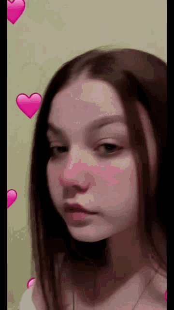 a close up of a young girl 's face with pink hearts around her