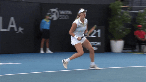 a woman is holding a tennis racquet on a tennis court in front of a la sign