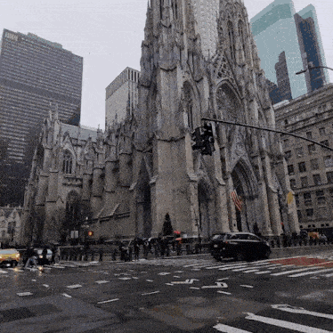 a car is driving down a wet street in front of a large building