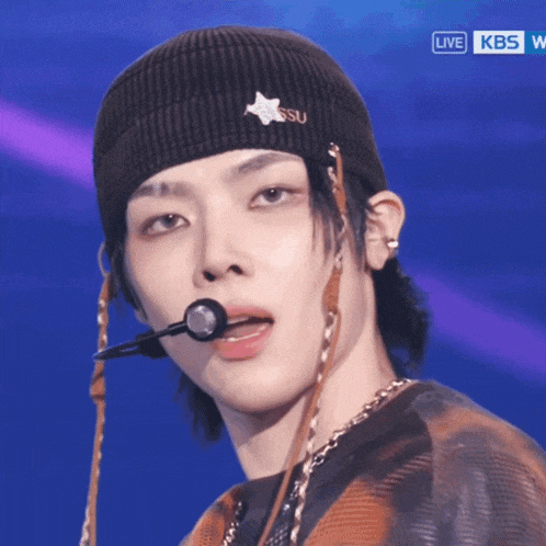a close up of a person wearing a beanie with a star on it and a kbs logo in the background