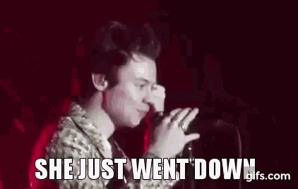 harry styles is singing into a microphone on stage while holding a microphone .