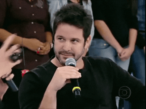 a man with a beard is holding a microphone and talking into it