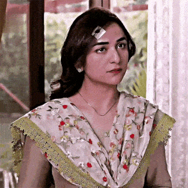 a woman with a bandage on her forehead is sitting in front of a window .