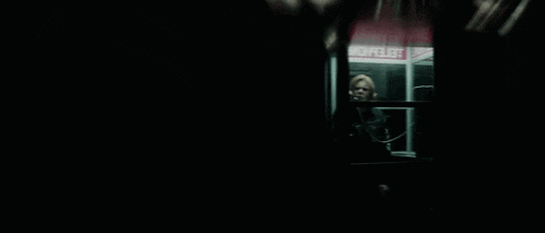 a man is talking on a phone in a pay phone booth .
