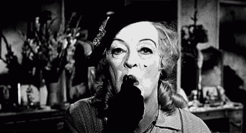 a black and white photo of a woman wearing a hat and a black glove .