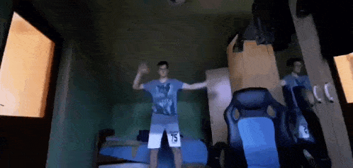 a man wearing shorts with the number 15 on them is dancing in a bedroom