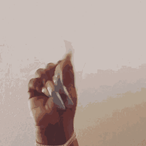 a close up of a person 's hand with long nails holding something .