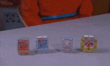 a person is sitting at a table with a bunch of toys on it including one that says ' disney ' on it