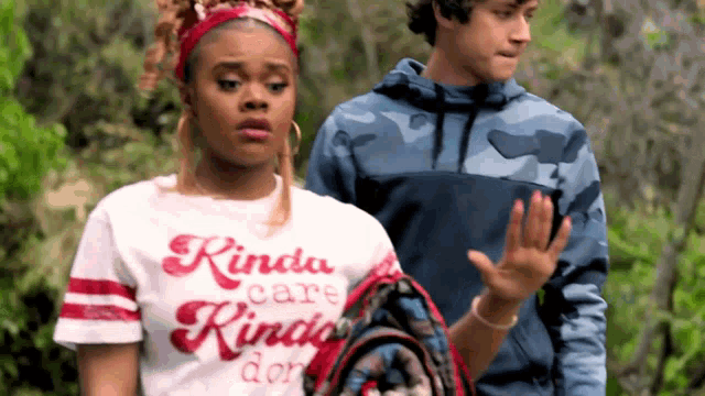 a girl wearing a kinda care kinda do t-shirt is standing next to a boy .