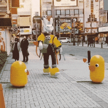 a rabbit and a duck are walking down a sidewalk in front of a building that says c7oden on it