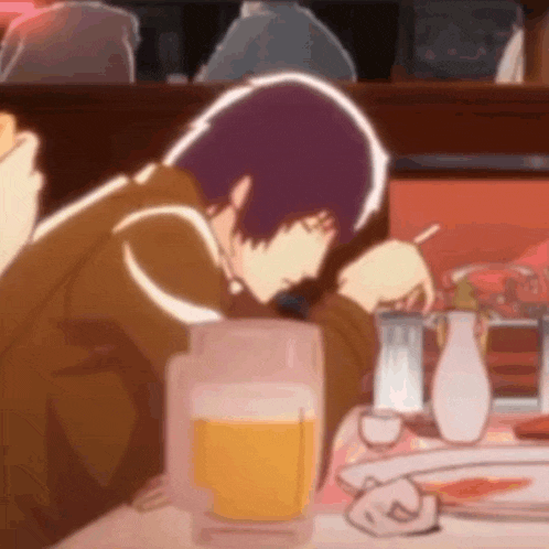 a man with purple hair is sitting at a table with a glass of beer .