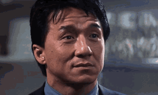 a close up of a man 's face with a blue shirt
