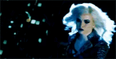 a woman with long white hair is standing in a dark room