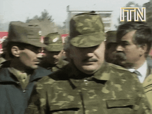 a man in a military uniform stands in front of a sign that says itn on it