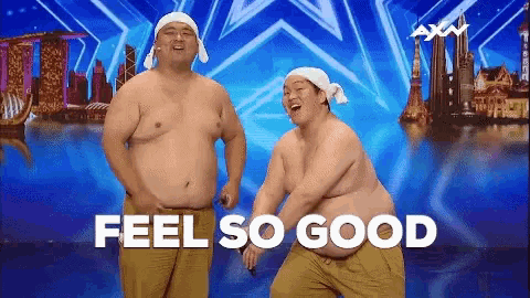 two shirtless men are dancing in front of a sign that says feel so good ..