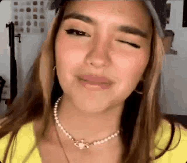 a close up of a woman wearing a pearl necklace and a hat .