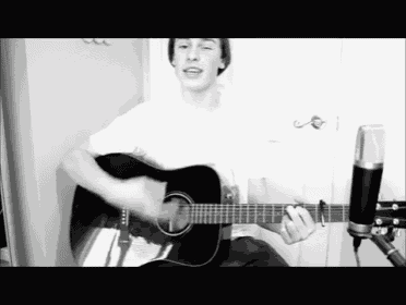 a black and white photo of a young man playing a guitar