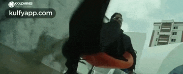 a man is sitting on a chair in front of a building with his foot on the chair .