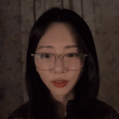 a woman wearing glasses and a plaid shirt is looking at the camera